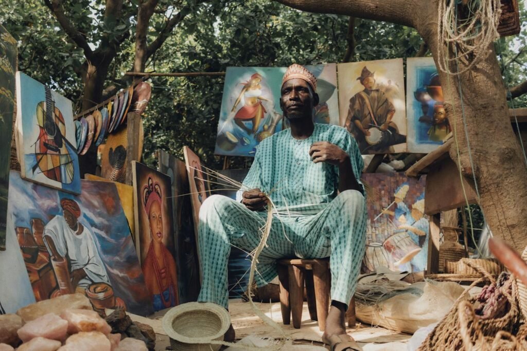 Explore the vibrant Nigerian art and craft market with traditional paintings and a skilled artisan at work.