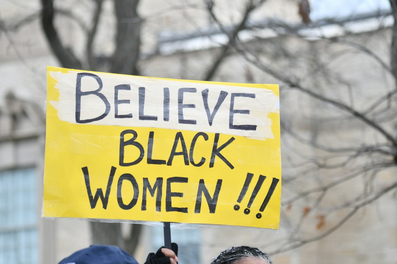 Sign says, "believe black women!!!" - afroféminisme