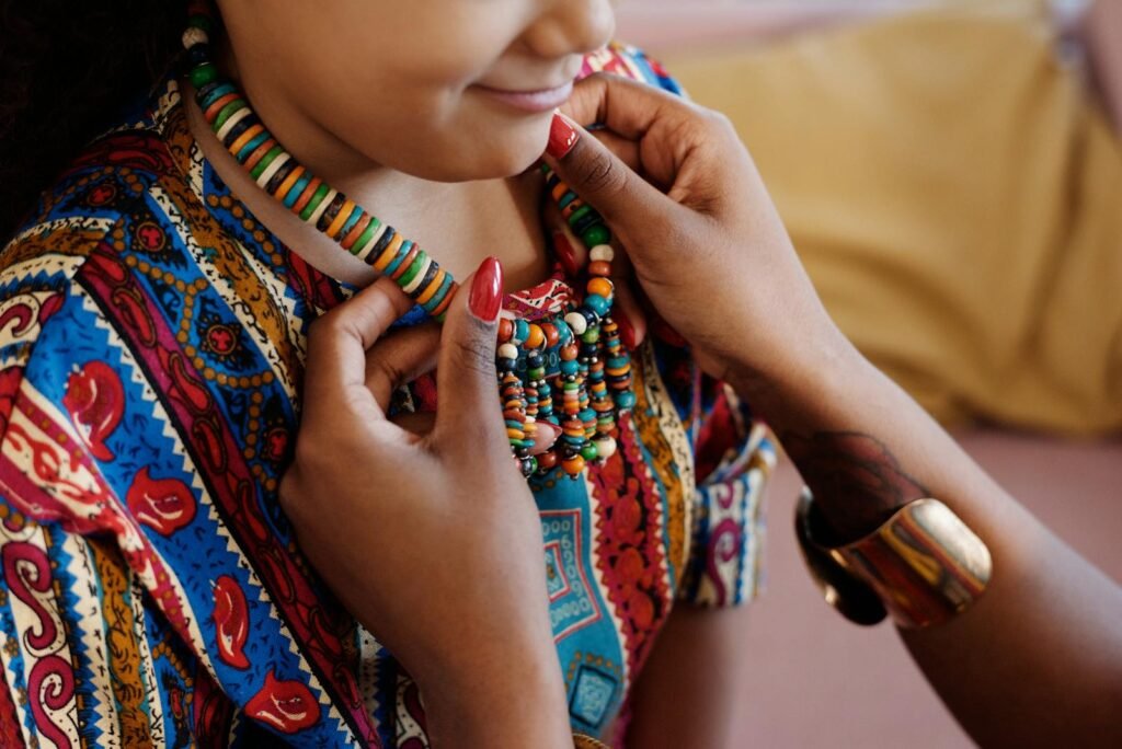 Young girl wearing a vibrant, colorful beaded necklace and traditional attire indoors - 7 principes de kwanzaa