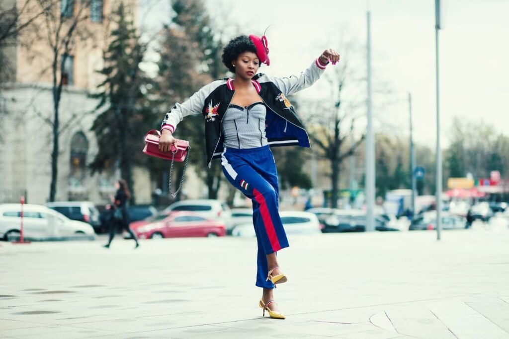 Fashionable African woman in vibrant attire jumps on a lively street in Kharkiv.