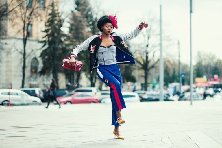 Fashionable African woman in vibrant attire jumps on a lively street in Kharkiv.
